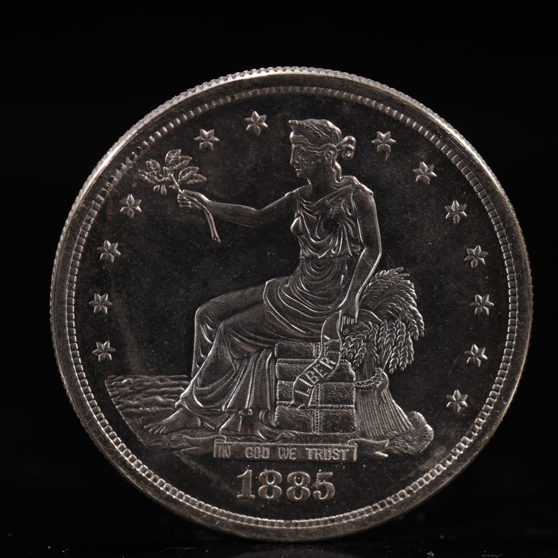 USA Trade Dollar 1885 Coin: American coin. Obverse: Liberty seated on a pedestal facing the sea to the left holding olive branches surrounded by 13 stars. IN GOD WE TRUST / LIBERTY / 1885. Reverse: An eagle holding branches with