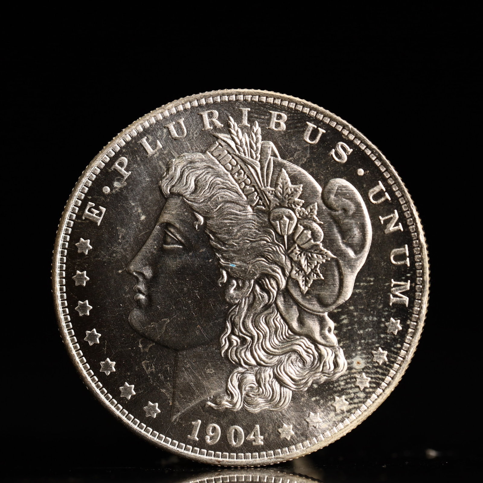 USA Morgan Dollar 1904 Coin: Obv: profile bust with date below and E PLURIBUS UNUM legend and stars around. Rev: eagle with In God we trust above within wreath with UNITED STATES OF AMERICA ONE DOLLAR legend. IN GOD WE TRUST /