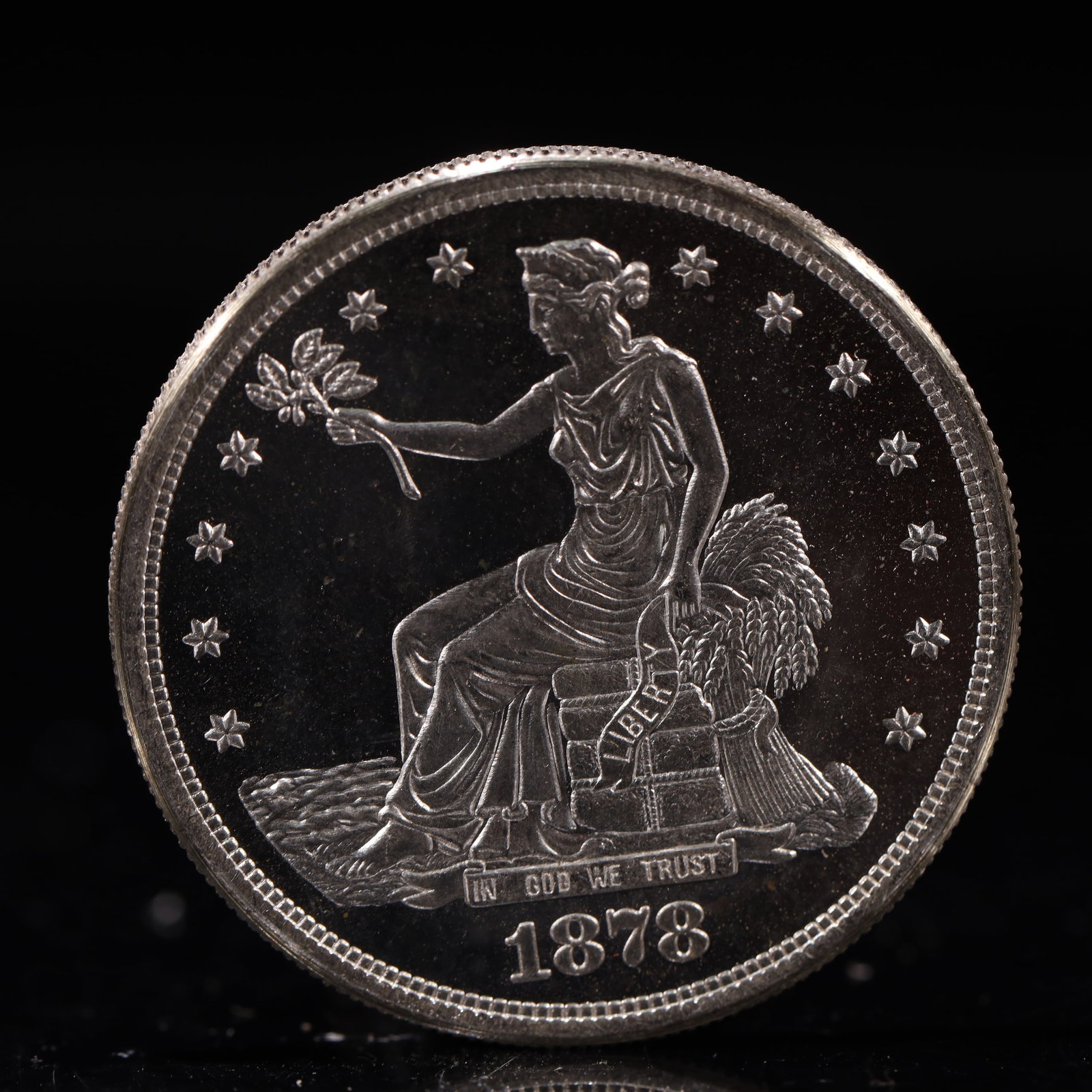 USA Trade Dollar 1878 Coin: American coin. Obverse: Liberty seated on a pedestal facing the sea to the left holding olive branches surrounded by 13 stars. IN GOD WE TRUST / LIBERTY / 1878. Reverse: An eagle holding branches with