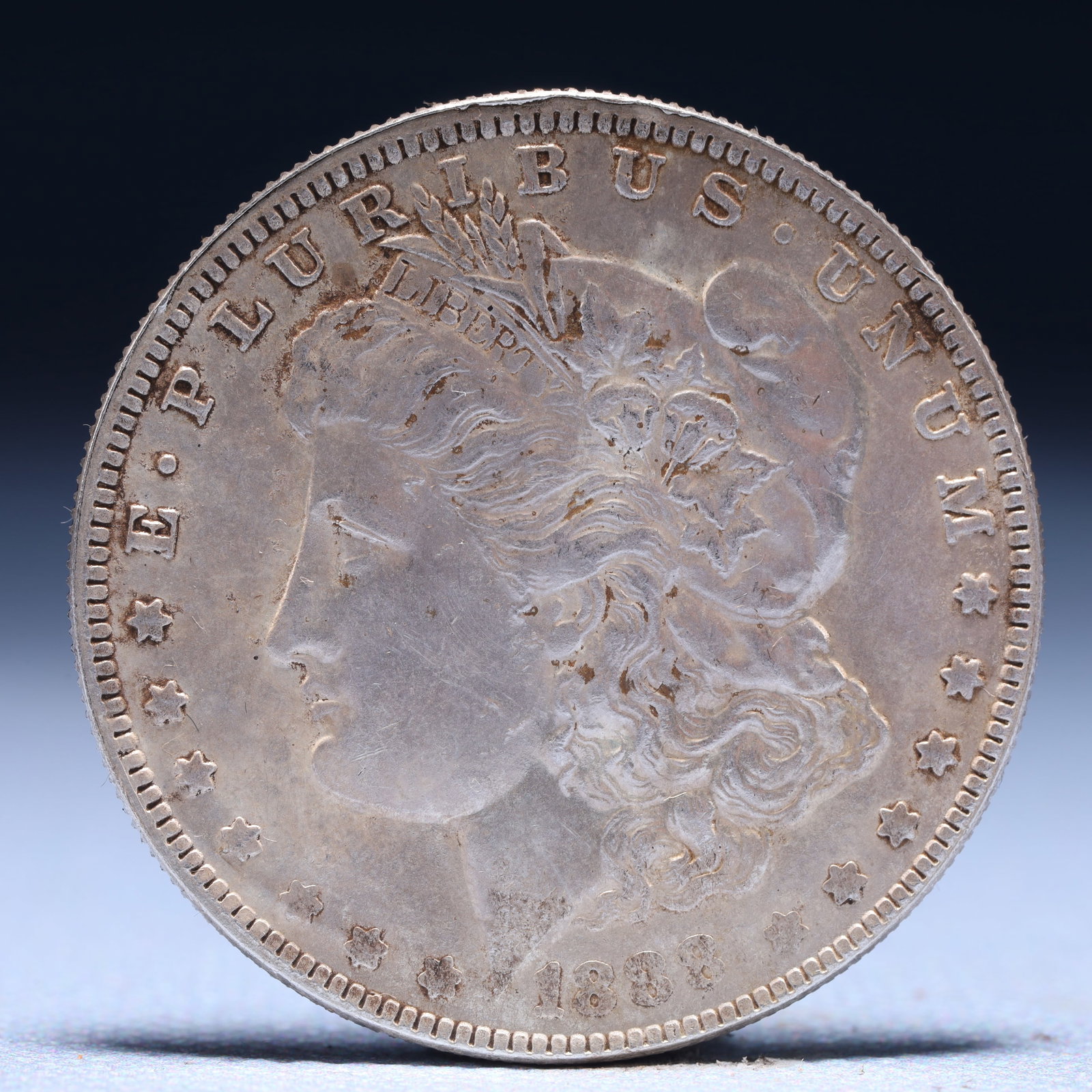 USA Morgan Dollar 1888 Coin: Obv: profile bust with date below and E PLURIBUS UNUM legend and stars around. Rev: eagle with In God we trust above within wreath with UNITED STATES OF AMERICA ONE DOLLAR legend. IN GOD WE TRUST / LI