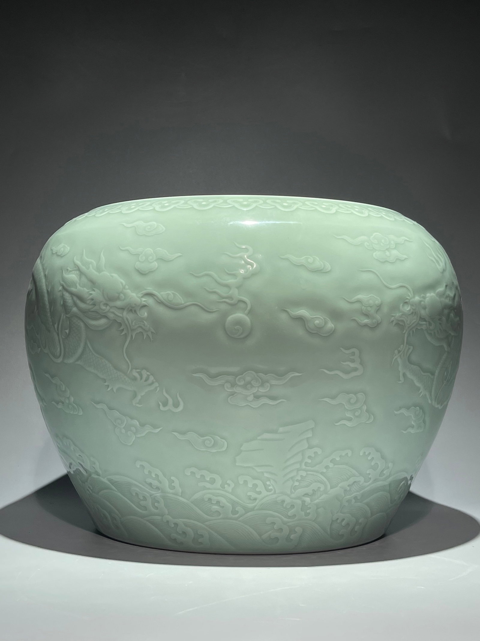 An Exquisite Celadon Glazed Auspicious Cloud and Dragon Pattern Vat: An Exquisite Celadon Glazed Auspicious Cloud and Dragon Pattern Vat,Qing Dynasty,China,Qianlong Six-character Mark,Size:10.4inx14.6in 青釉祥云龙纹缸,中&