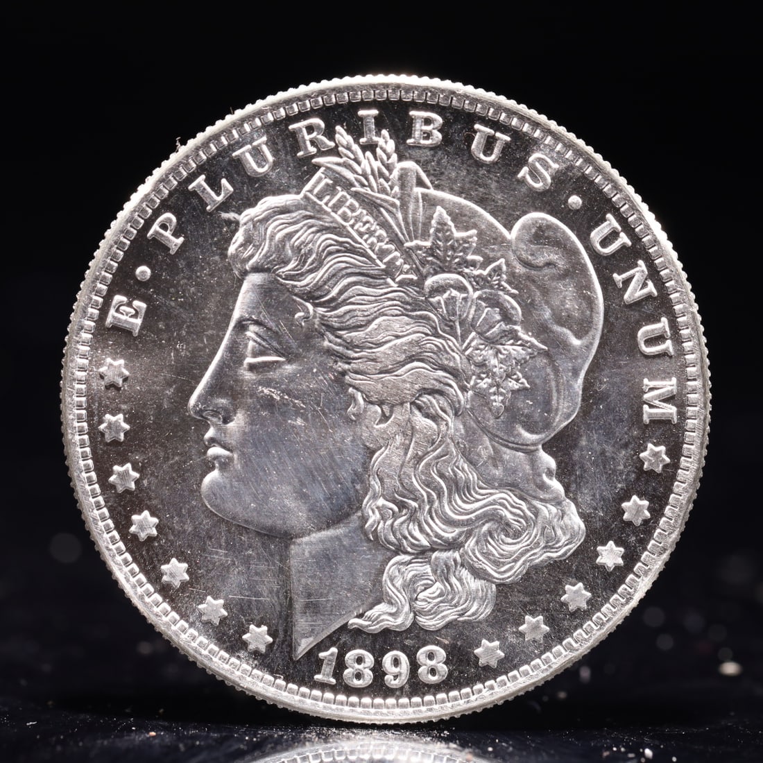 USA Morgan Dollar 1898 Coin: Obv: profile bust with date below and E PLURIBUS UNUM legend and stars around. Rev: eagle with In God we trust above within wreath with UNITED STATES OF AMERICA ONE DOLLAR legend. IN GOD WE TRUST / LI