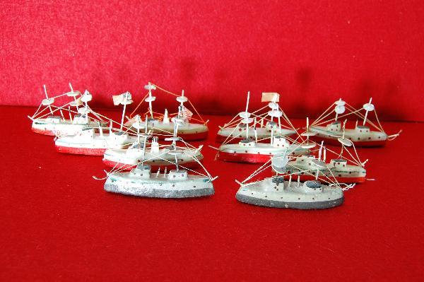 (10) wood mini models of Naval ships: (10) wood mini models of Naval ships - some with American flags; hand-painted red, white & black & 2 painted grey & black. c. 1925 Condition: some restrung; some bending to masts; paint surfaces very