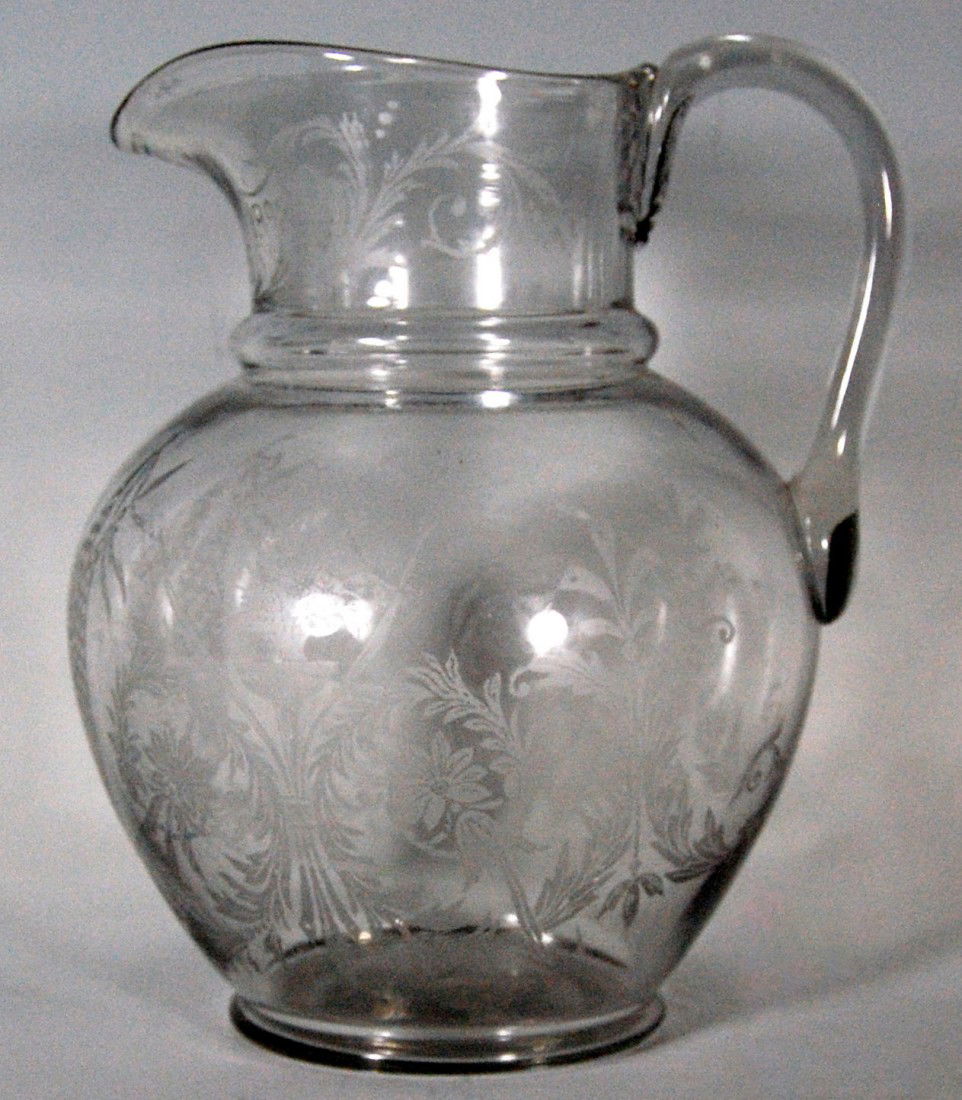 Pitcher, Columbus 1492-1892, Columbian Expo.: Crystal pitcher, souvenir of the Columbian Exposition, with etched portrait of Columbus, scroll and foliate design with the dates 1492-1892. Mold blown with applied handles. Size: 9" x 7" x 3 1/2" D W