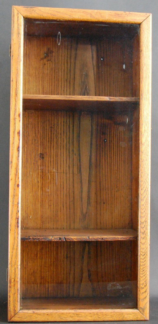 Glazed Oak, Wall Hanging Cabinet, c. 1900: Cabinet constructed of oak with two fixed shelves, also oak. The door is glazed with the original glass within a mitered frame. Hinges and hook and eye latch are brass. American, c. 1900. Size: 25.5 x
