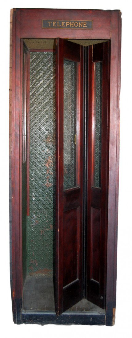 Telephone Booth From Iowa Hotel, c. 1920: Telephone booth having a mahogany frame with folding glazed door. The interior finished in tin with the original green paint on the walls and yellow on the ceiling . Oak floor is also in the original 