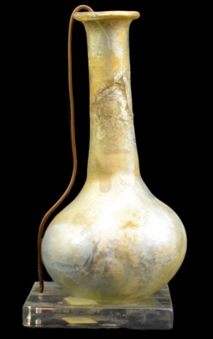Vase, 3.75" Syrian excavated glass: Vase, 3.75" Syrian excavated glass, possibly 100-300 A.D., rounded bottom - mounted on plexiglass & wire for display. Size: 3-3/8" H x 1.75" diameter base Weight: Condition: excavation quality; intact