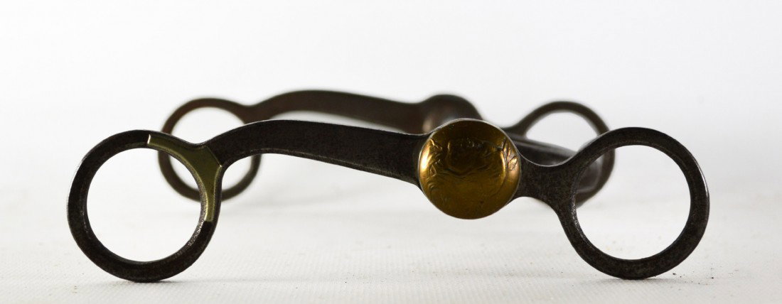 Horse Bit with brass Indian Head rosettes 19th C: Bit with brass Indian Head Rosettes, 19th Century. Brass Indian head rosettes mounted on both sides of the bit. Provenance: Miki and James J. Mangan III of Fairfield, CT Size: L. 6.25" x W. 6" Weight: