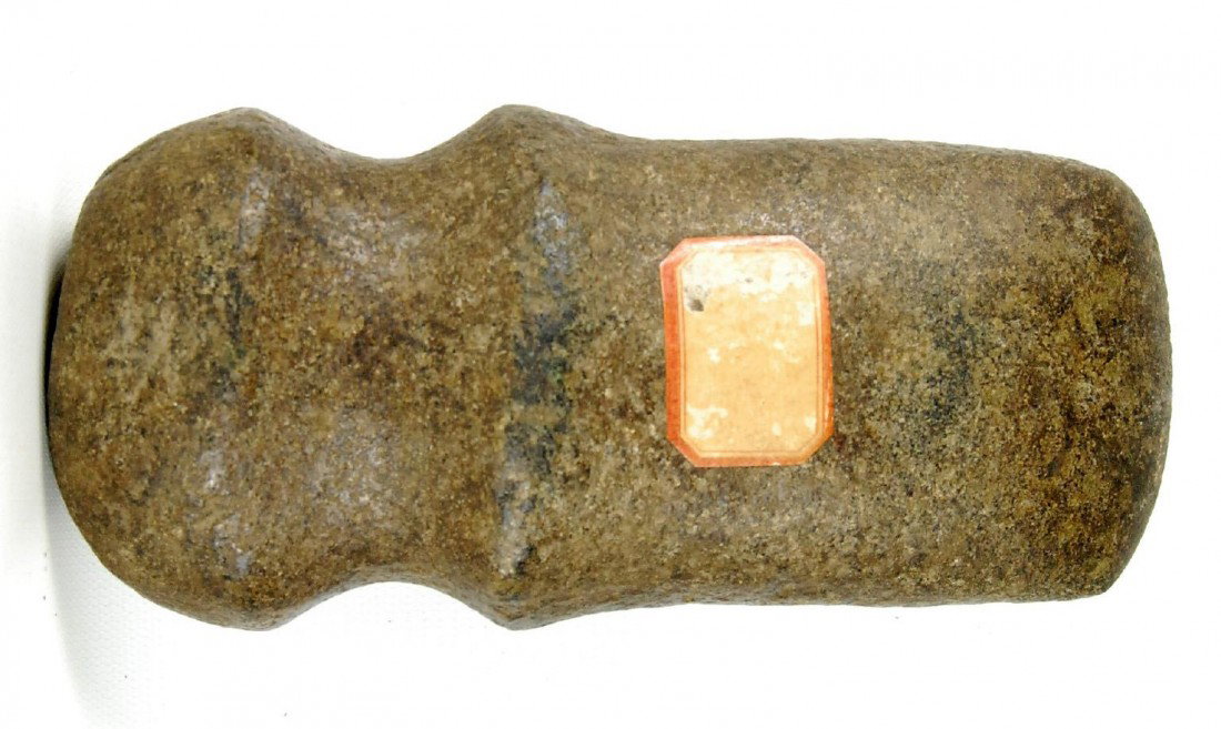 Native American Stone Axe: Medium size native American stone axe with full groove, made from porphyry stone well polished. Retains an old jelly label collection sticker which is unreadable. Size: L. 7.25" x W. 3.25" x D. 2.25" 