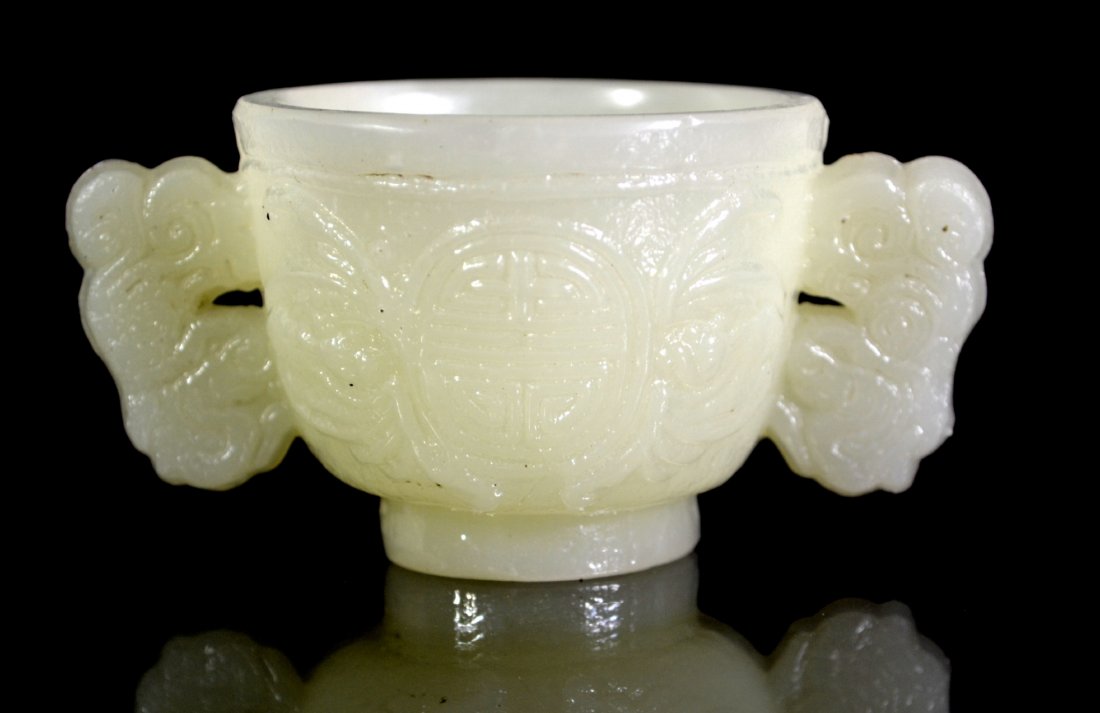 Libation Cup, Chinese Peking Glass: Form: Libation Cup Colors: White Decoration: Carved decoration depicts scroll with writing and bats on the body and handles. Color imitating jade. Possibly Ming dynasty. Provenance: Ina & Sandford Gad
