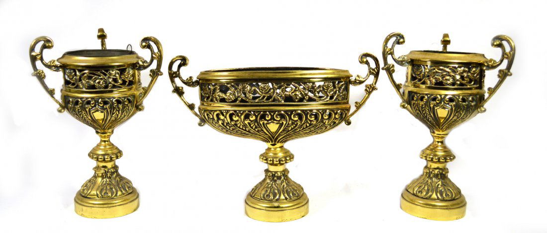 Fireplace Garniture Set (3), Brass, English, 1860: Fireplace garniture set Material: Brass Construction: Cast w/ hand finishing Features: English made. Floral and foliate decoration. Each retains the original tole liner. Period: Circa 1860 Size: 17.25