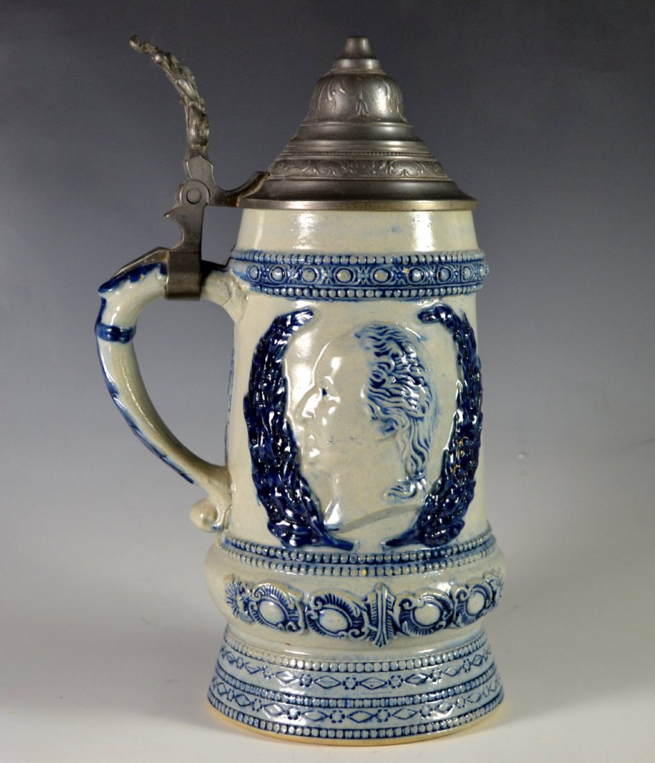 Stein, Stoneware, Paul Revere: Stein Material: Stoneware Construction: Hinged Marks: "38" Colors: Blue & gray Features: One side depicts Paul Revere alerting Colonial militia of approaching British forces before the battles of Lexi