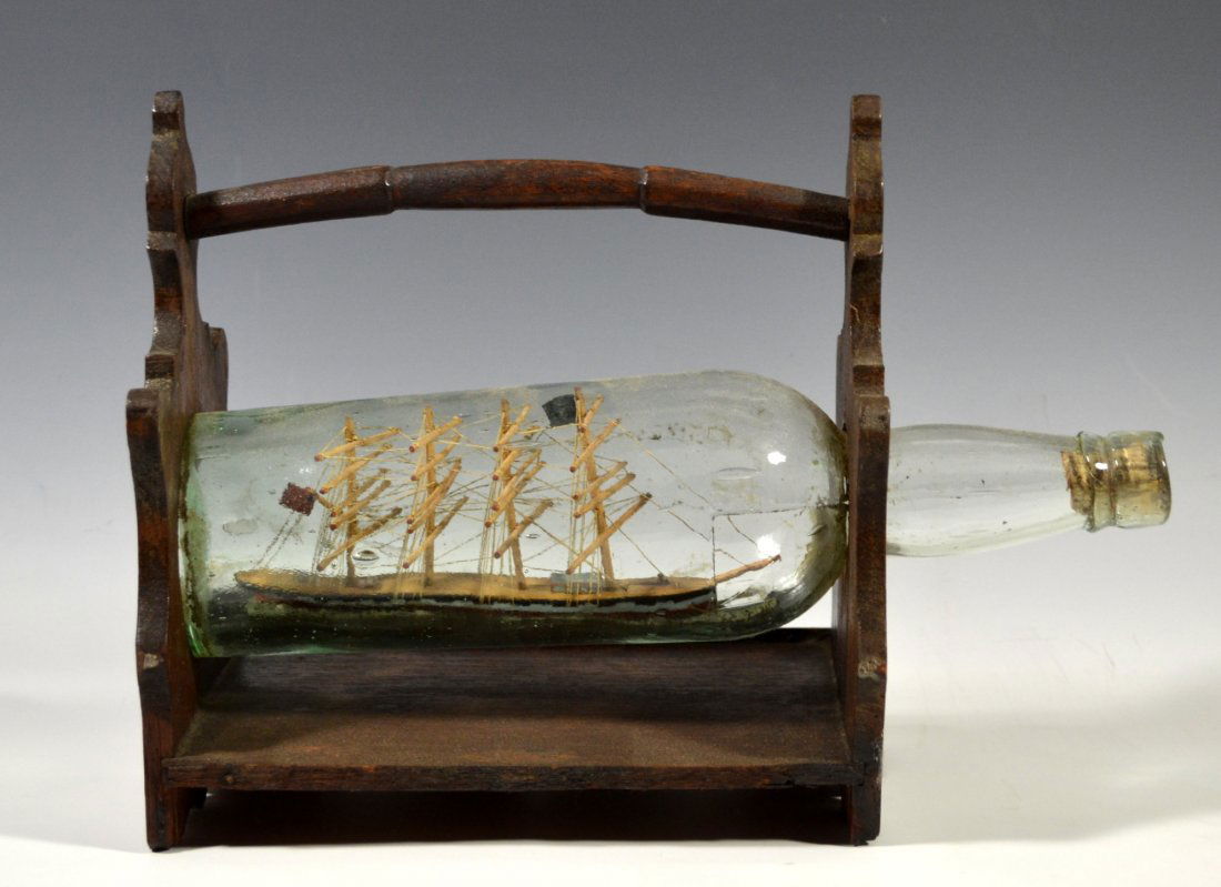 Ship in a Bottle, Bark: Country of Origin: Great Britain Type: Bark Hull: Black, light blue, and red Rigging: Stays on masts Deck Furniture: Three small houses Decoration: Ship in bottle composed of four masts. Has red and b