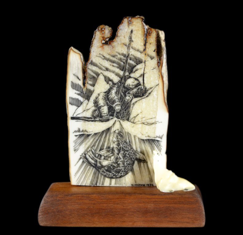 Mounted Scrimshaw, Fossilized Walrus, Ivory: Fossilized Walrus Age: 1993 Materials: Wood, Ivory Maker: Geoff Olson Description: A mounted scrimshaw walrus of fossilized mammoth ivory with engraving. Engraving depicts Eskimo resting/fishing and s