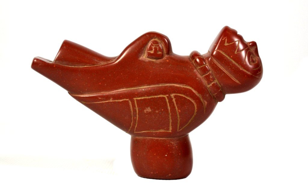 NW Pacific CoastPipe, Catlinite, Winged Figure W/ Child: Pipe Materials: Catlinite Description: Northwest Pacific Coast Pipe depicts a winged figure holding a child. Possibly from Haida tribe Provenance: A Connecticut Collector Size: 4" L x 1" W x 2.5" D We