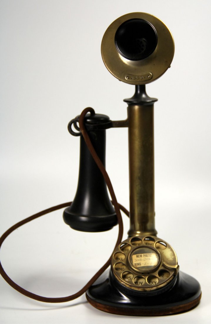 Telephone, Candlestick, Western Elec., 1924: This brass candlestick phone features a base with a vertical cylindrical neck extending upright for up to 10 inches in length. At the top of the stand is mounted a carbon microphone (transmitter) to s