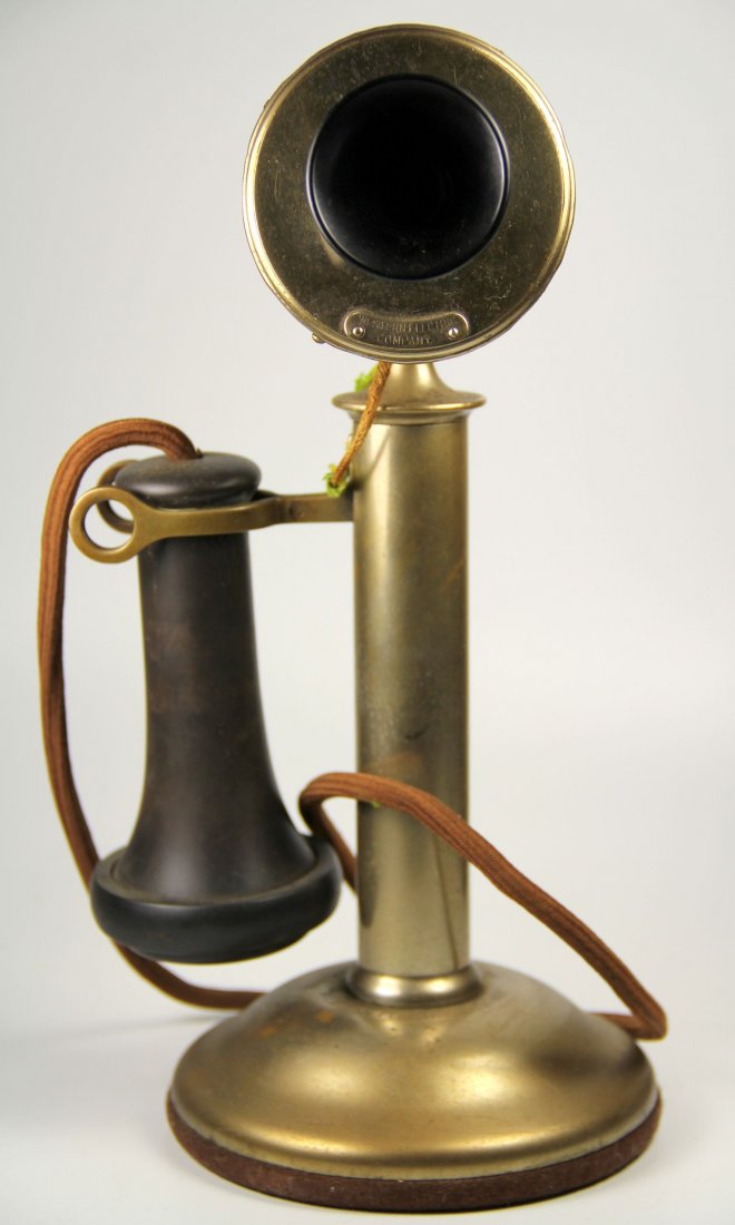 Telephone, Candlestick, Western Elec, Patent 1904: This brass candlestick phone features a base with a vertical cylindrical neck extending upright for up to 10 inches in length. At the top of the stand is mounted a carbon microphone (transmitter) to s