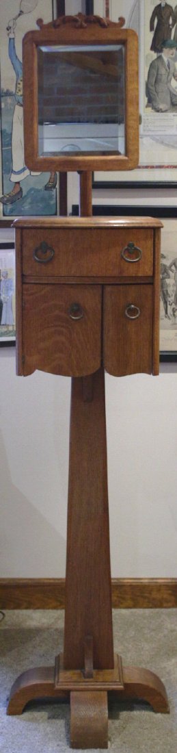 Stand, Shaving w/Adj. Mirror, Pedestal Base c1910: Description: An oak shaving stand with bevel glass mirror, has a pedestal base with a single drawer and two doors. Material: Oak Maker/Artist: Unknown Date: Circa 1910 Provenance: n/a Size of