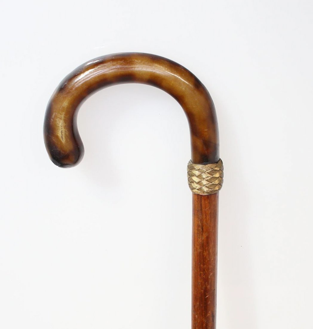 Cane, Bent Horn Handle & Rosewood shaft, c. 1870: Description: A walking stick or cane with a Bentwood rosewood shaft. There is also a woven ring pattern in a gold tone color between the stick and the bent horn handle of the walking stick. Material: