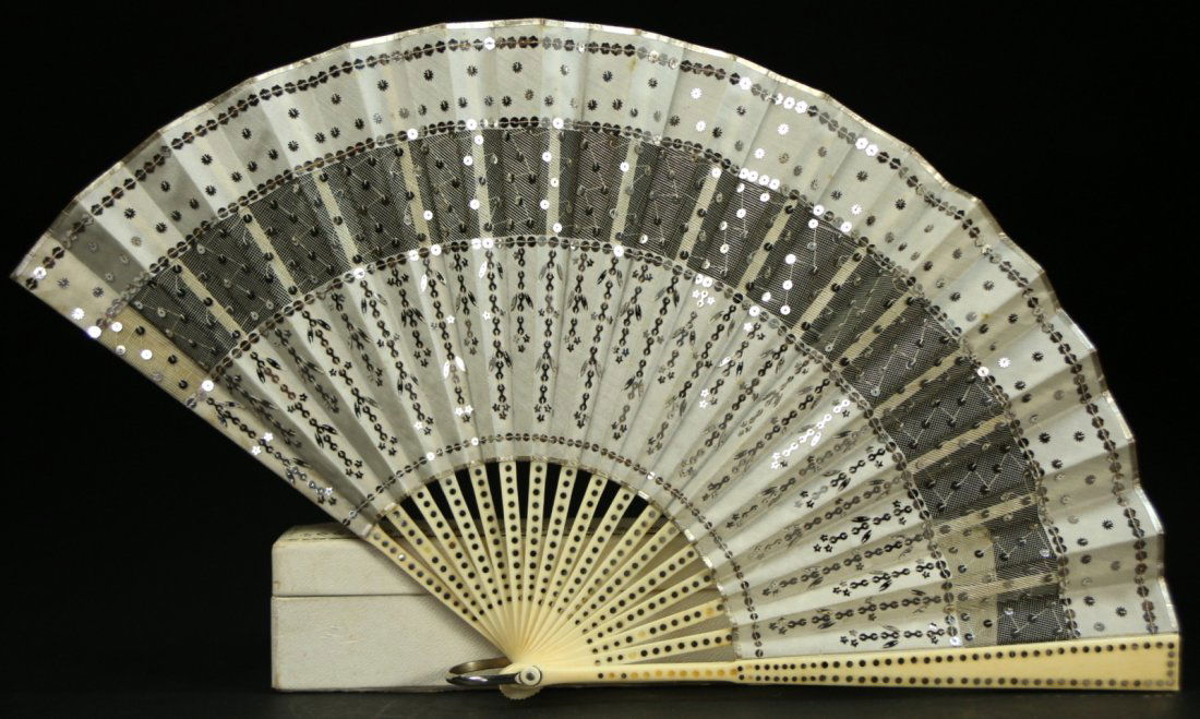 Fan, Folding, Bone Staves, Sequins, Boxed: Description: Folding hand fan, made with bone staves and silver sequins all sewn on a fabric trimmed with silver, the center fabric piece is a lace fabric. The original box, has a label from B. Altman