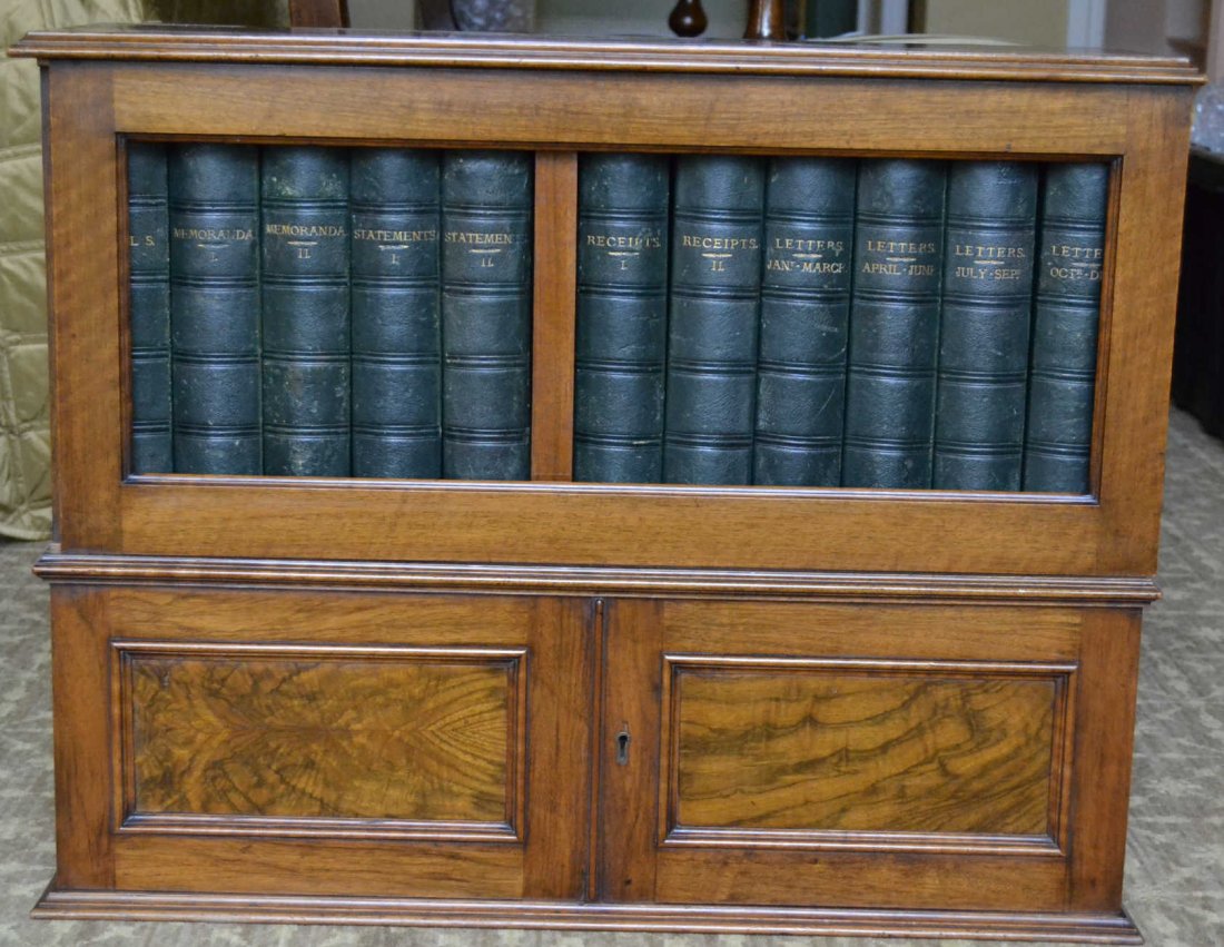 Stone's Patent Box, c. 1870: Description: Constructed of walnut solids and veneers. Sliding door with side lock opens to a set of book form boxes. Burled top, flat panel, two door base. Original chromoliths inside each box and 'S