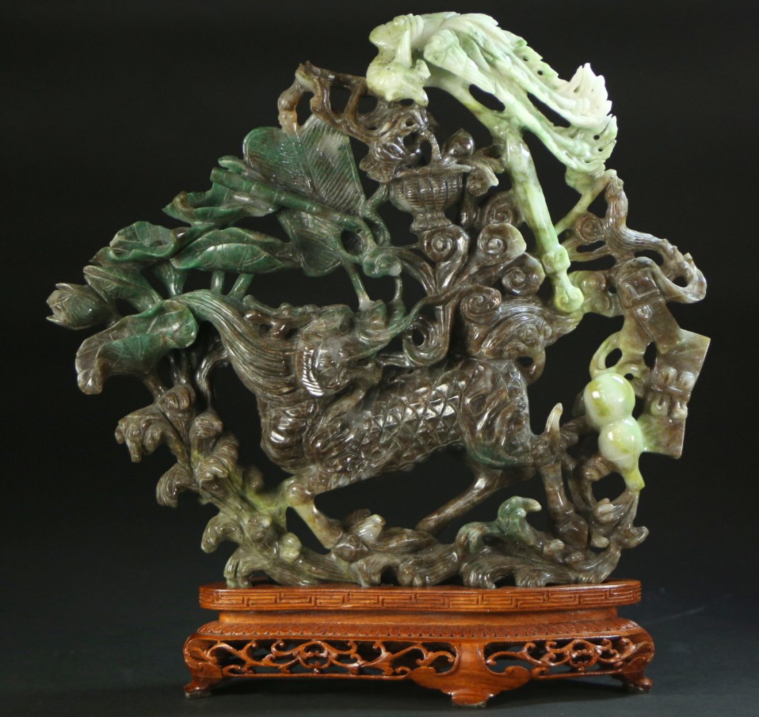 Carved Jade, Foo Dog on stand. Circa 1975: Description: A jade carving with a stand of a foo dog, entwined with vines. There is also a phoenix bird in the vines as well. The wood stand has a Greek key pattern around the rim, the base has a ret