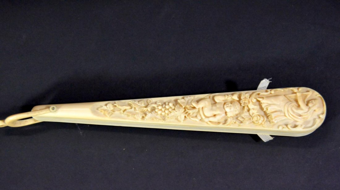 Fan, carved ivory, hand-woven silk, c.1870: Description: A fine hand carved ivory fan, Composed of sixteen plain tapered ribs connected by woven silk ribbon and two guard sticks, both sides of the guard sticks are highly relief carved. One side
