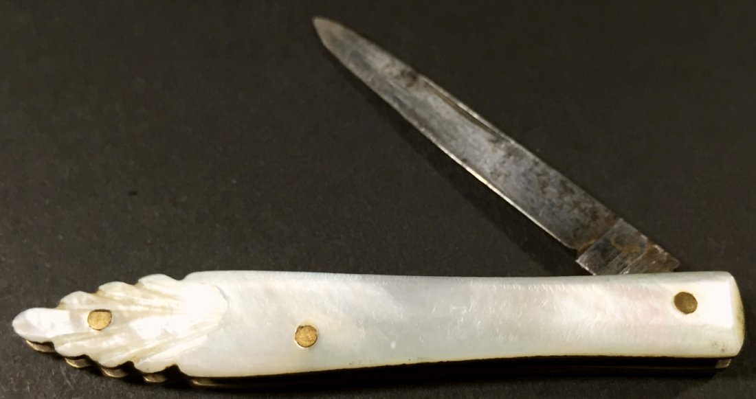 Scrimshander's Knife, Rare, C. 1830: Description: Compass rose engraved on bottom of the whale and elephant ivory handle. Blade folds into the handle. Brass pins and caps hold the handle pieces together. History: Scrimshaw is the name gi