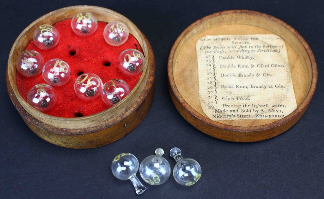 Hydrostatic Balls For Proving Spirits: Description: Circular wooden box contains twelve "hydrostatic balls" that were used in the 18th and early 19th century to measure the strength or "proof" of alcoholic spirits. A label of description i