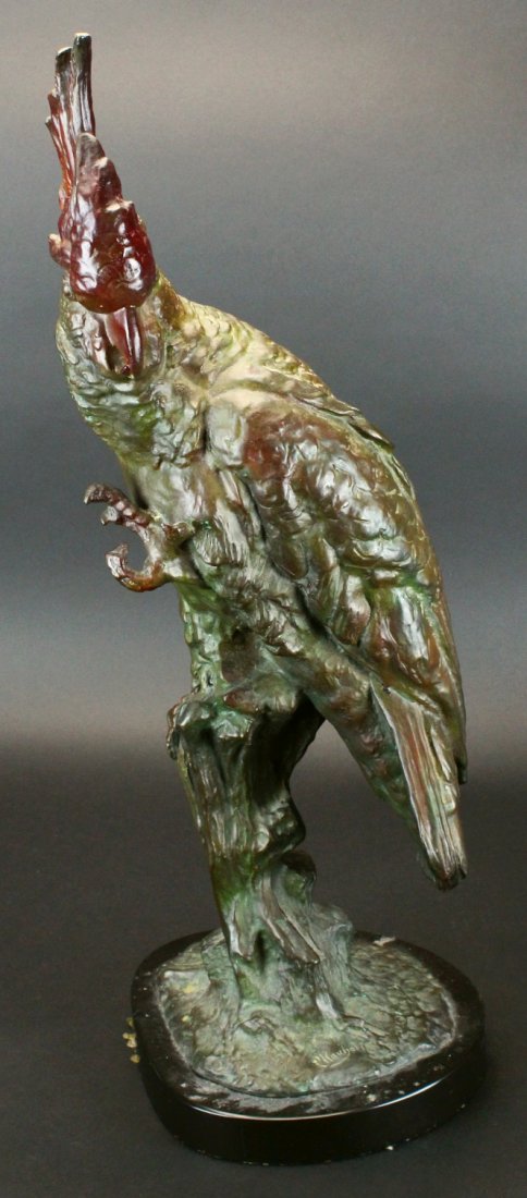 Bronze Parrot by Carl Kauba: Description: Patinated and cold paint highlighted bronze of a parrot standing on a stump with one foot raised. Signed within the casting C. Kauba and mounted on a black marble base. History: Kauba, Ca