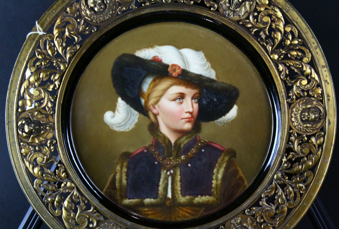 Painted Porcelain Plaque, Gilt Surround: Description: A fine presentation of a woman wearing a fur trimmed cape, pearls and a fine feathered hat. A gilt metal original surround serves as a frame for the piece. History: Art Nouveau KPM style
