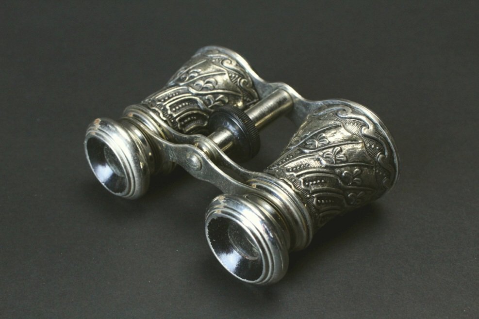 Silver Plated, Made in Occupied Japan: Description: Cast brass barrels, silver plated in a stylized wave pattern below a leaf design. Marked 3x on the top bridge and Made in Occupied Japan on the bottom bridge. History: Opera glasses, also