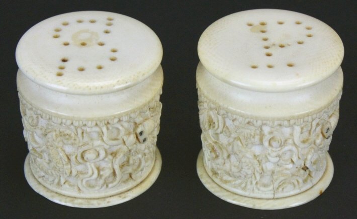 Ivory Salt and Peppers, Relief Carved, 1890: Description: A pair of Chinese relief carved ivory salt and pepper shakers. Carved dragons and scrollwork around entire body. History: Early in the Neolithic Age, the Chinese ancients already started 