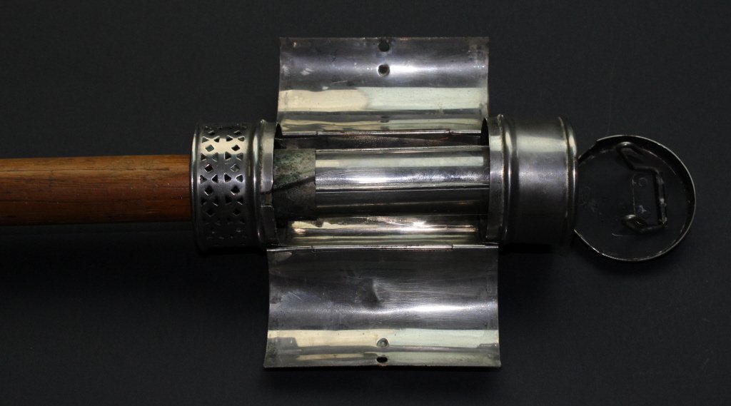 Gadget Cane, Camping Light, Beech, C. 1900: The beech shaft of this cane or walking stick is topped with a camping light gadget. The tool has two thin doors, kept close with the turn of a screw. Inside is a pillar on which a candle can be lit t