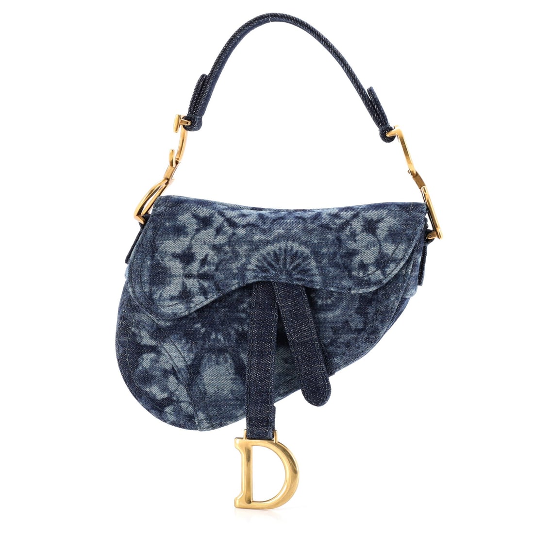 Christian Dior Saddle Handbag Tie Dye Printed Denim: Carried right, the Saddle reads as the house's working signature: the asymmetric, stirrup-clasp silhouette John Galliano drew up for Dior in 1999. The 6 by 8 by 2 inch format reads as compact rather t