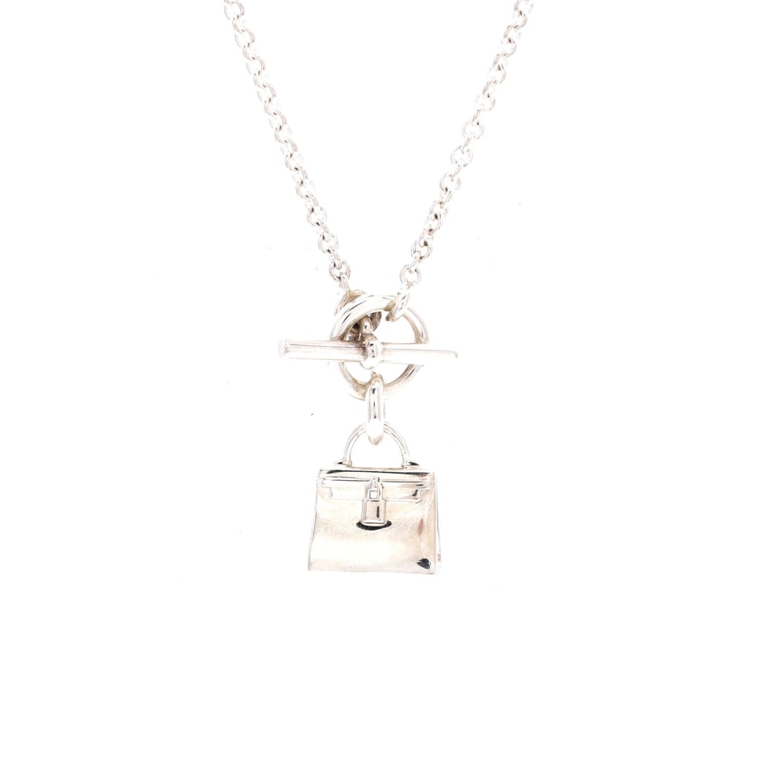 Hermes Amulettes Kelly Pendant NM Necklace Sterling Silver: Sterling silver, half an inch of it, shaped into the Kelly's flap and strap and hung from a 16" chain - the Amulettes NM is the pendant Hermes drew from its most recognizable silhouette. The short cha