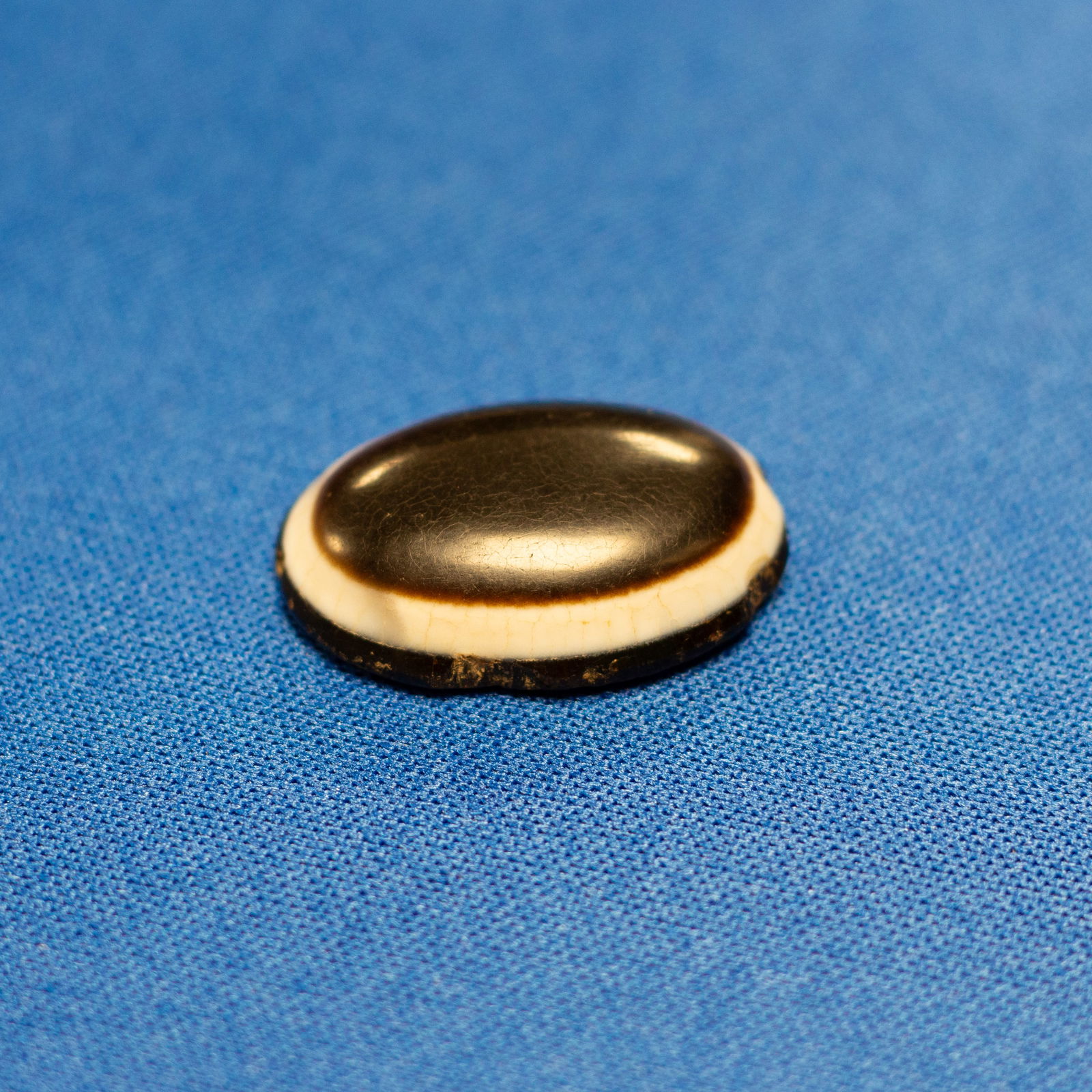 PENDANT: EYE SASANIAN (224-651 CE): This oval pendant, intentionally designed to resemble an eye, features a polished domed surface and is likely made from black agate, onyx, or obsidian - materials commonly used in antiquity for amulet