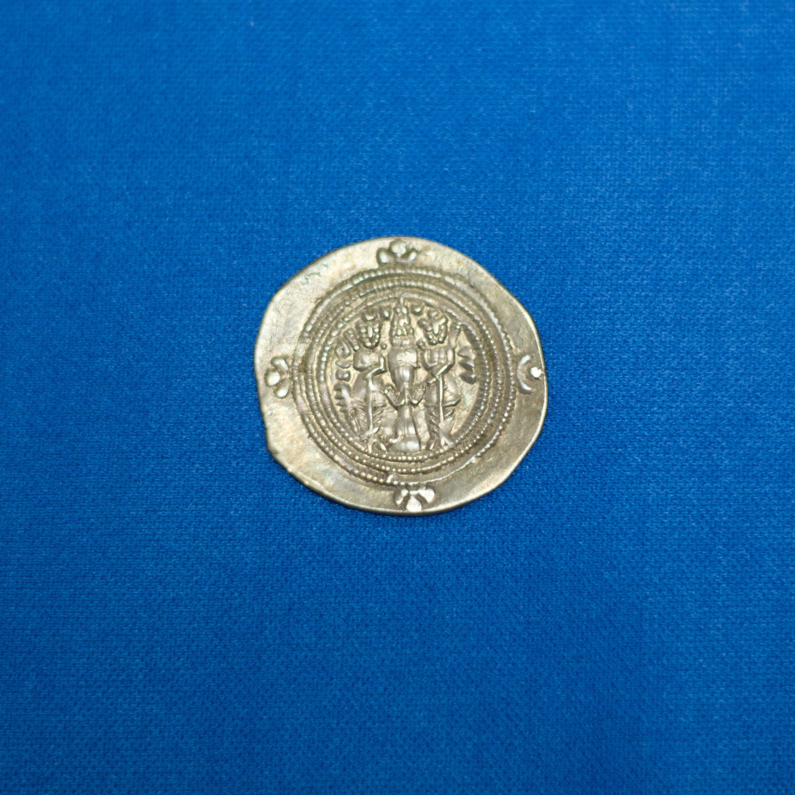 COIN: DRACHM SASANIAN (224-651 CE): This Sasanian silver drachm of King Khusro II (590–628 AD) features the iconic crowned bust of the ruler facing right, wearing the tall winged crown flanked by astral symbols that symbolize divine s