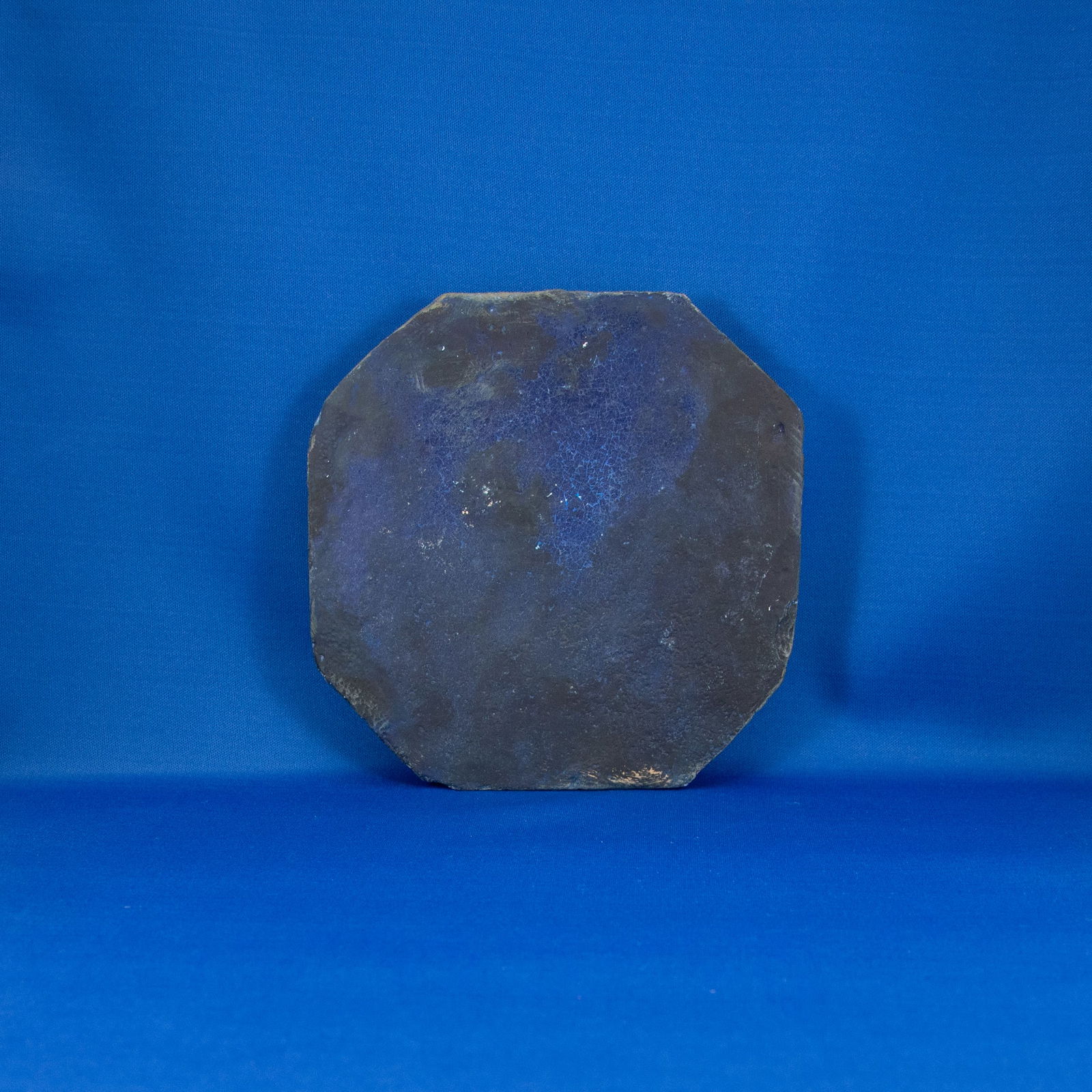TILE: OCTAGON COBALT BLUE SAFAVID (1501-1722 CE): A rare Safavid monochrome architectural tile, glazed on the front in a deep, atmospheric cobalt blue, characteristic of 17th-century Persian mosques and palatial revetments. The tile is shaped as a mo