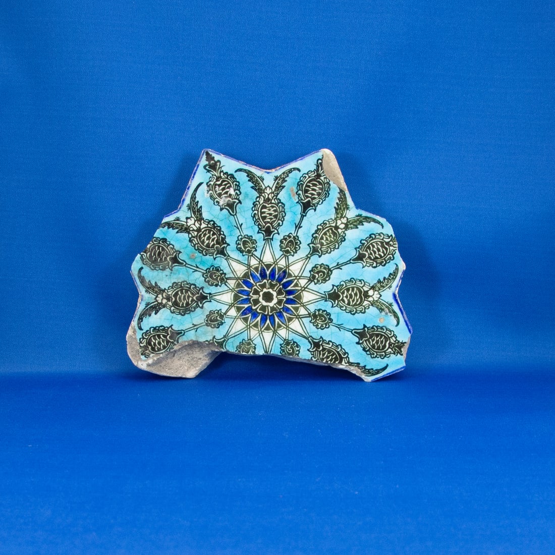 TILE: STAR SAFAVID (1501-1722 CE): A fragment of a Safavid period underglaze-painted star tile, originally part of an eight-pointed architectural tile (Khatim Sulaym?n). The surviving section preserves an exceptionally crisp and vibran