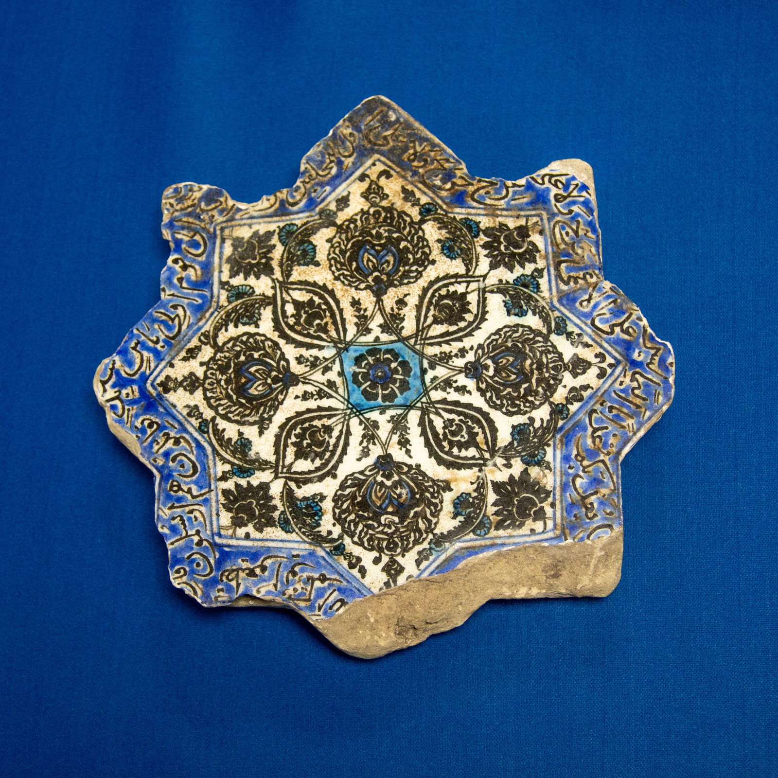 TILE: STAR SAFAVID (1501-1722 CE): A finely crafted Safavid underglaze-painted star tile (Khatim Sulayman), shaped as an eight-pointed star and decorated in a classic three-colour palette of black, turquoise, and cobalt blue on a white