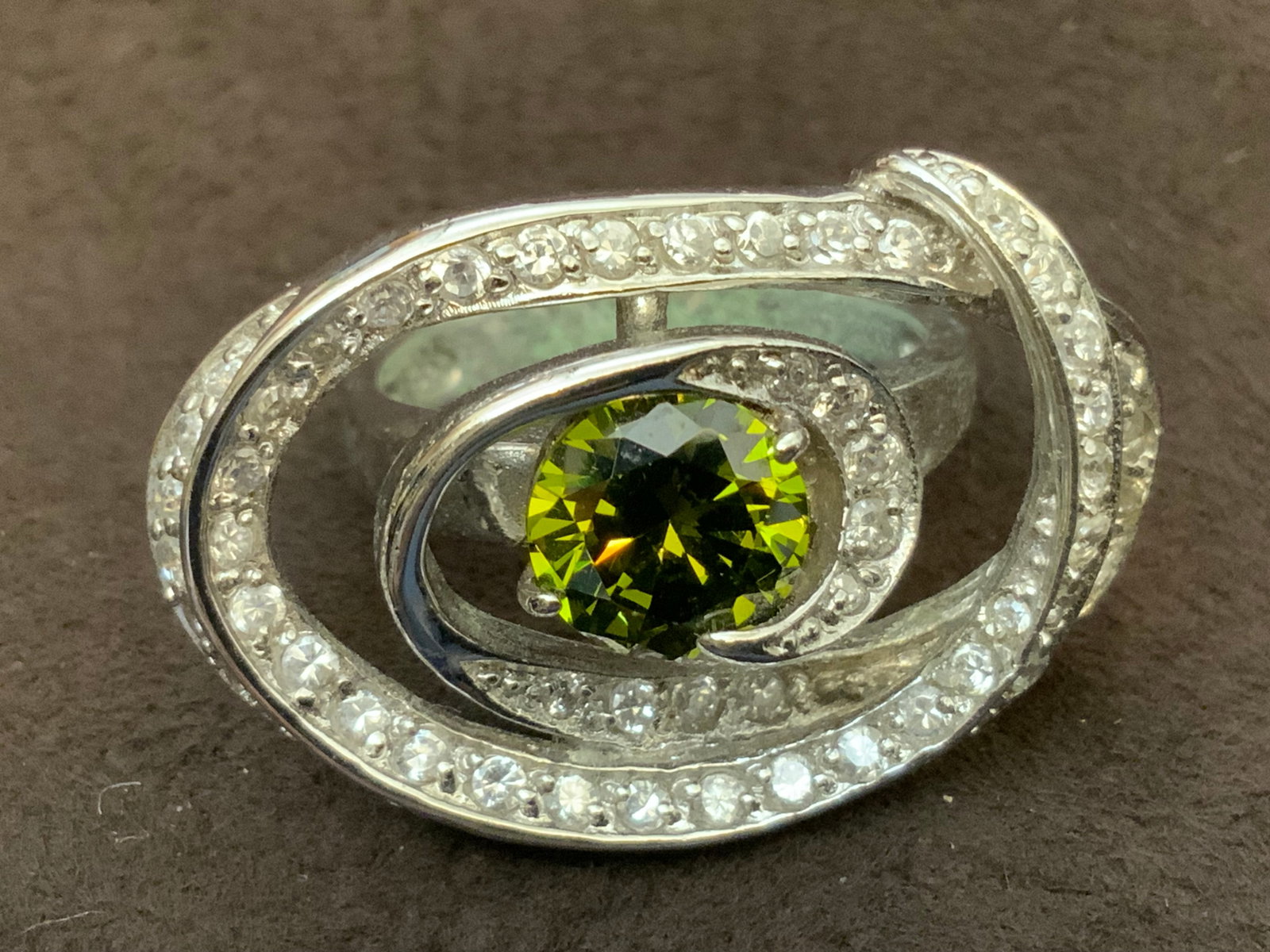 925 CZ Bridge-style Ring with Central Green Gemstone: 925 CZ Bridge-style Ring with Central Green Gemstone. Marked 925. .>>>>>>>>>>>>>>READ—-READ—-READ—-Shipping for this lot is available ONLY THROUGH LIVEAUCTIONEERS/LIVESHIPPING. We advise all bid