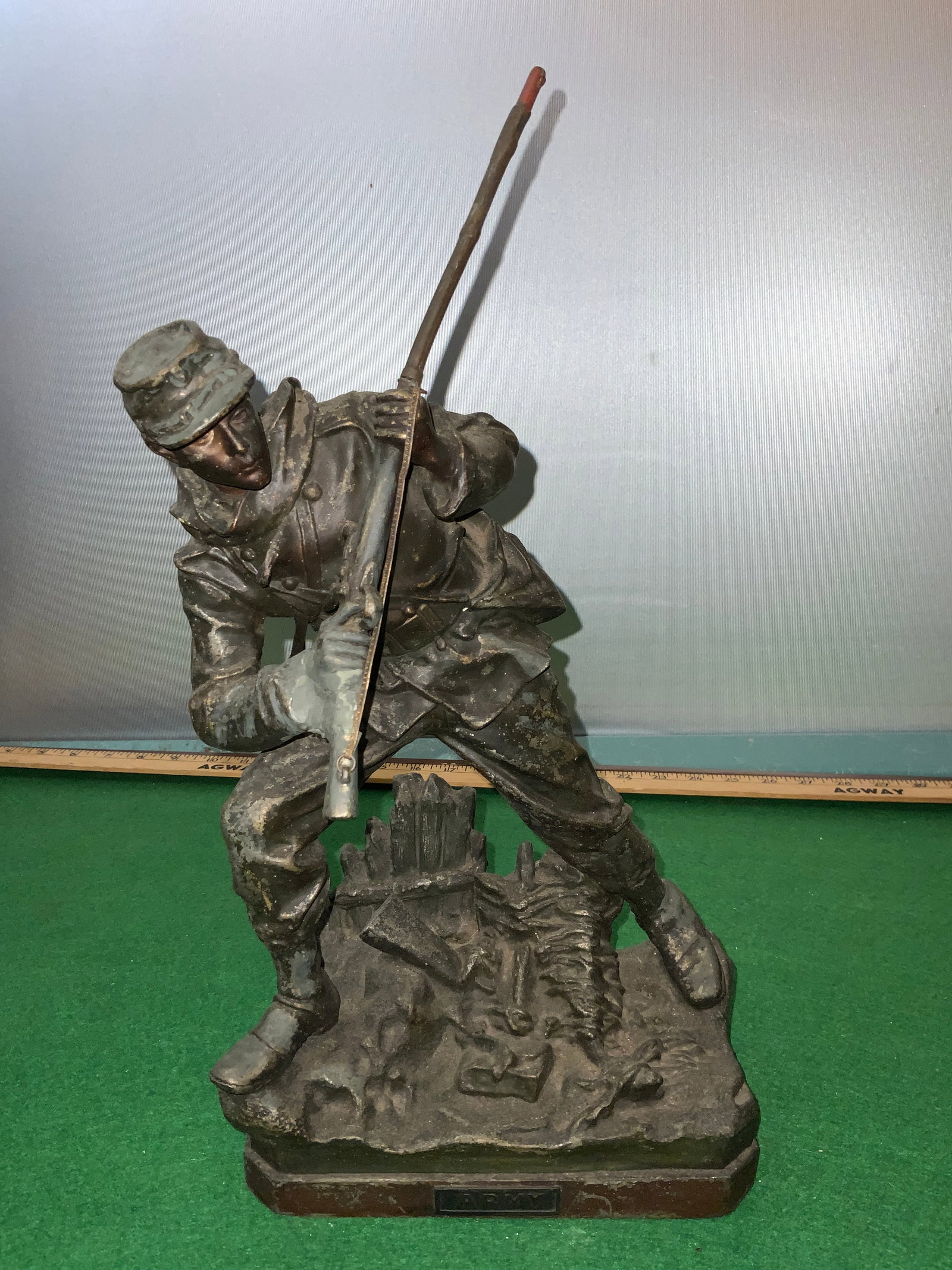 Antique Metal Army Soldier Figure in Battle Stance: Antique Metal Army Soldier Figure in Battle Stance. Rifle barrel is loose but attached. Unknown metal. Could be bronze, brass, or shelter with a bronze finish. Non magnetic. 5" 7 1/2" base, 16" tall.