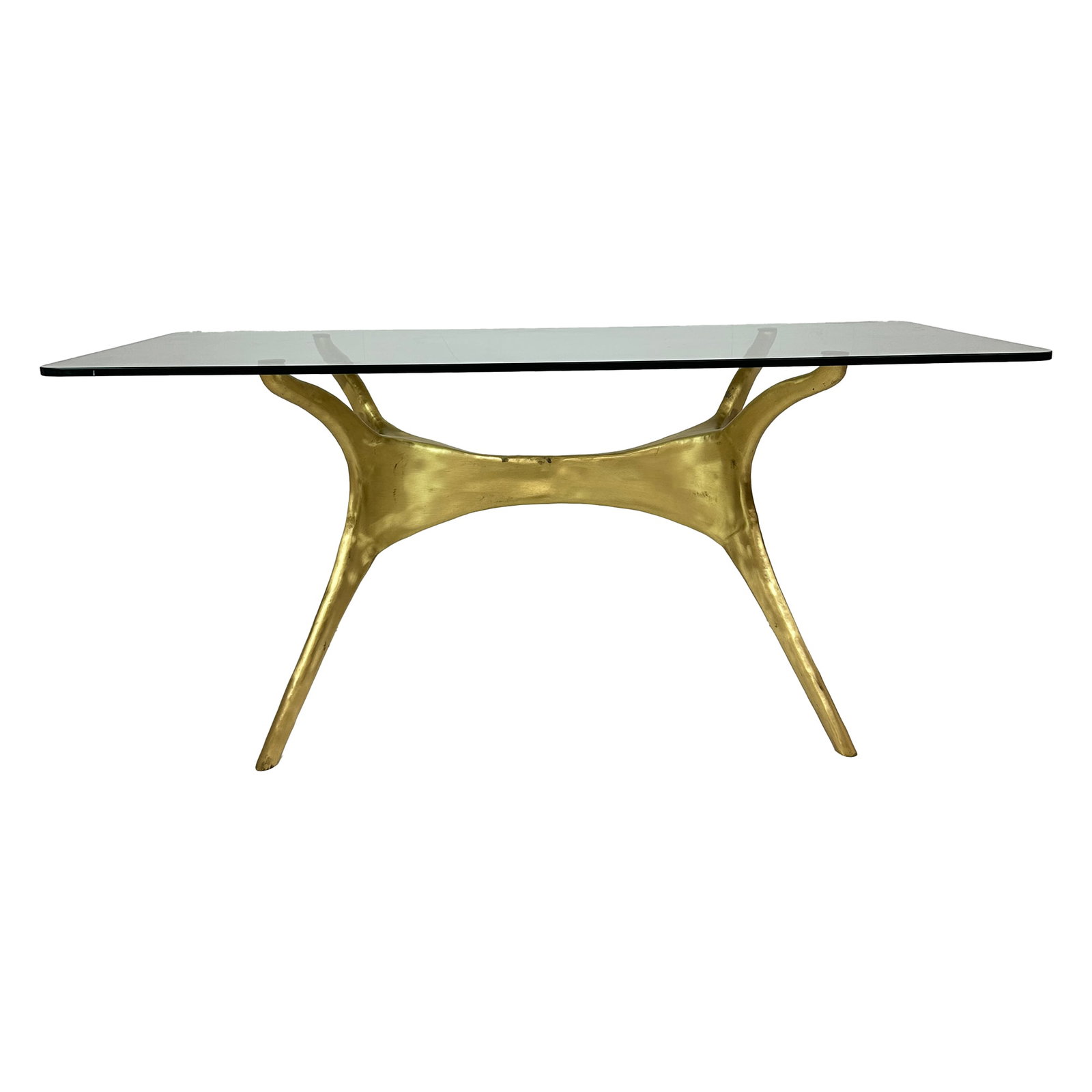 Sculptural Solid Brass & Glass Dining Table: A visually arresting dining table featuring a sculptural solid brass base with an organic, fluid form. Topped with a rectangular sheet of clear glass, the design pairs bold geometry with a luxurious f