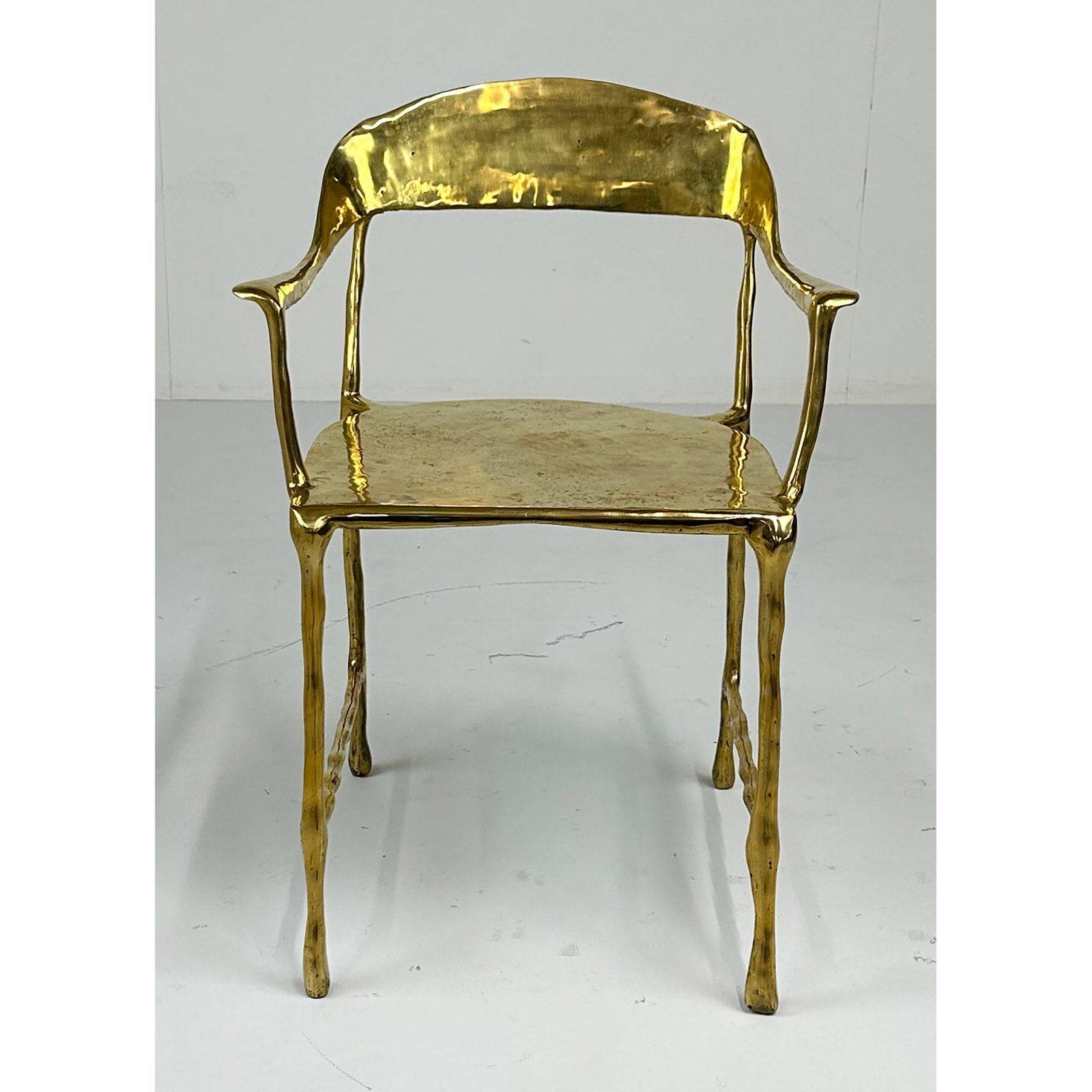 Sculptural Solid Brass Modernist Armchair: A stunning sculptural armchair cast in solid brass with a high-polish finish. Standing 30 inches tall, this piece showcases a fluid, organic silhouette with sinuous lines and tapered legs that give
