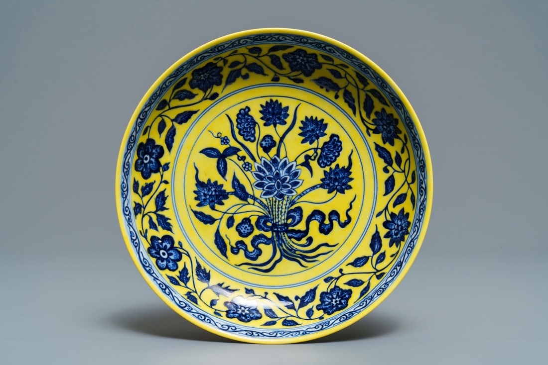 A CHINESE YELLOW-GROUND BLUE AND WHITE 'LOTUS BOUQUET' PLATE, QIANLONG MARK, 19/20TH C. (1 of 2)