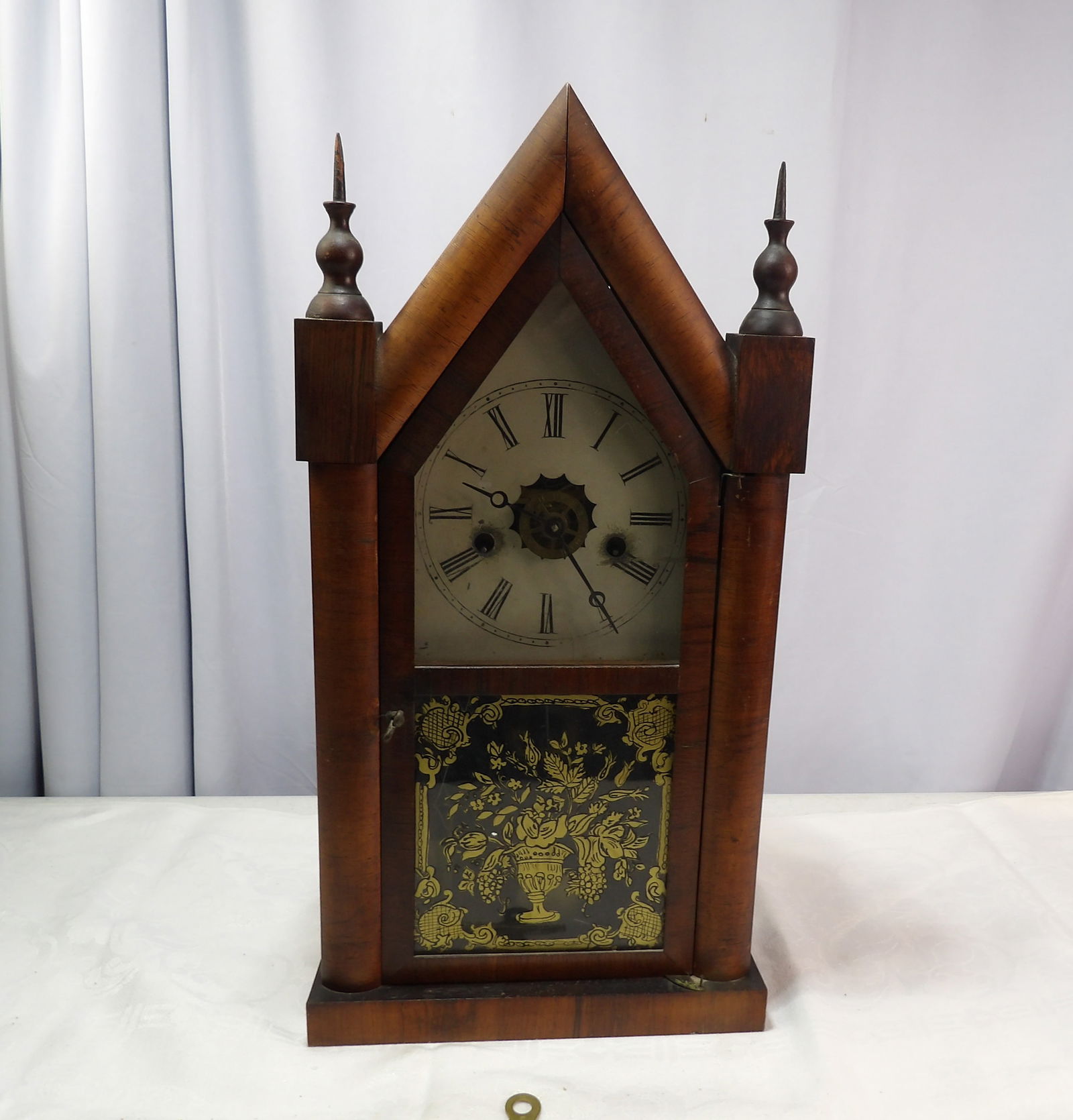 Antique Mahogany Steeple Clock: Antique American Mahogany Steeple Clock with Reverse Painted Glass. All measurements approximate. Please see photos for condition and details. Selling as is from 04281.