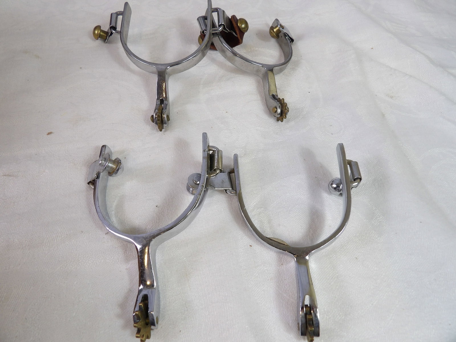 2 Pair-Stainless Western Spurs: 2 Pair of Stainless Western Spurs with Rowels. All measurements approximate. Please see photos for condition and details. Selling as is from 04281.
