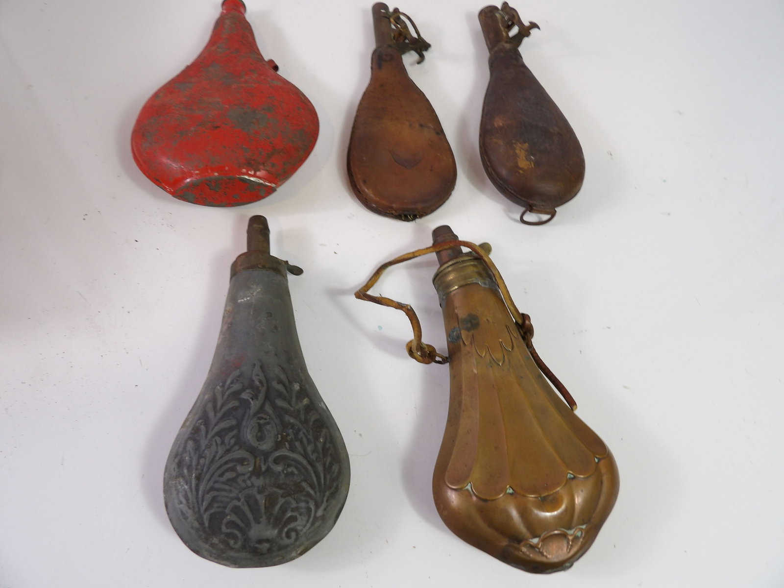 Collection of 5 Powder Flasks: Collection of 5 Vintage Powder Flasks, 2 are Leather, 1 is Brass, 1 is Zinc, and 1 is Tin. All measurements approximate. Please see photos for condition and details. Selling as is from 04281.
