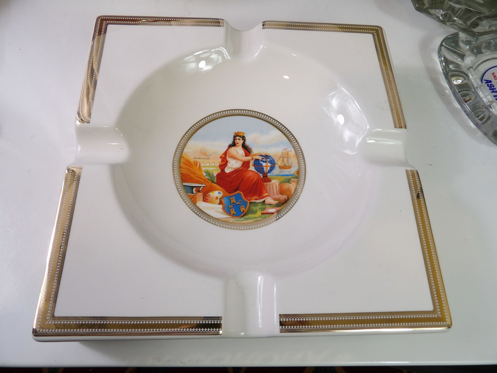 La Corona Porcelain Ashtray: La Corona Porcelain Ashtray with Central Figural Decoration. 9 1/2" Square. All measurements approximate. Please see photos for condition and details. Selling as is from 04281.